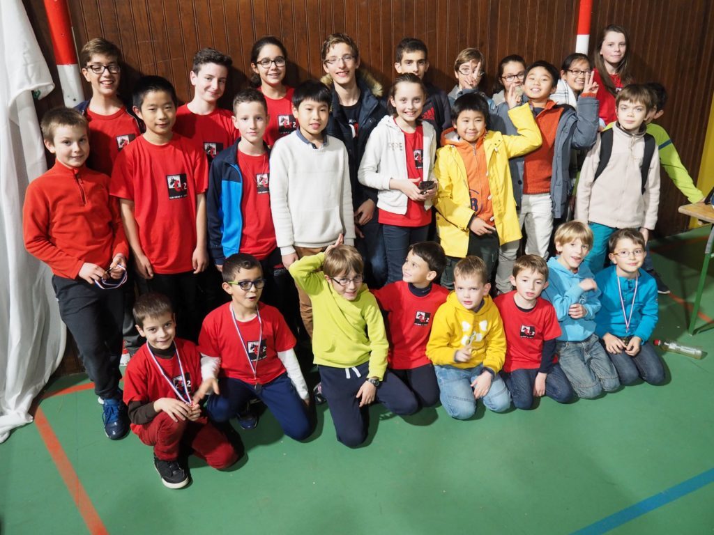 Grand groupe de jeunes du club en tee-shirt rouge réunis au gymnase pour le Championnat de l'Essonne Jeunes.