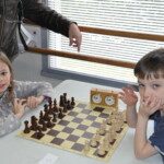 Deux jeunes joueurs et l'arbitre autour d'un échiquier avec pendule, Grand Prix Jeunes de l'Essonne.