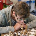 Un jeune joueur penché sur ses pièces, très concentré, lors de la compétition interdépartementale.