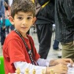 Jeune joueur souriant devant son échiquier au Championnat de France jeunes de Montbéliard.