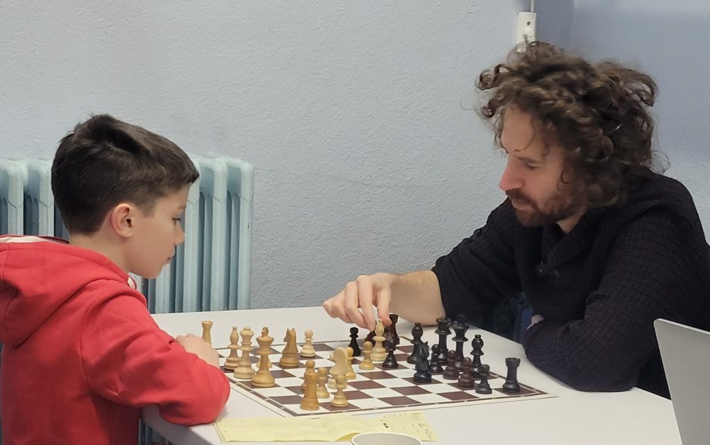 Un jeune joueur affronte un adversaire adulte qui déplace une pièce, aux championnats jeunes d'Île-de-France.