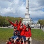 Les jeunes de l'équipe en tenue rouge posent joyeusement devant un monument lors de la N1 Jeunes.