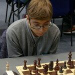 Un jeune joueur à lunettes penché sur son échiquier lors des Championnats jeunes de l'Essonne.