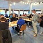 Vue d'ensemble de la salle du 22e Open de Gif, un arbitre circulant entre les tables.